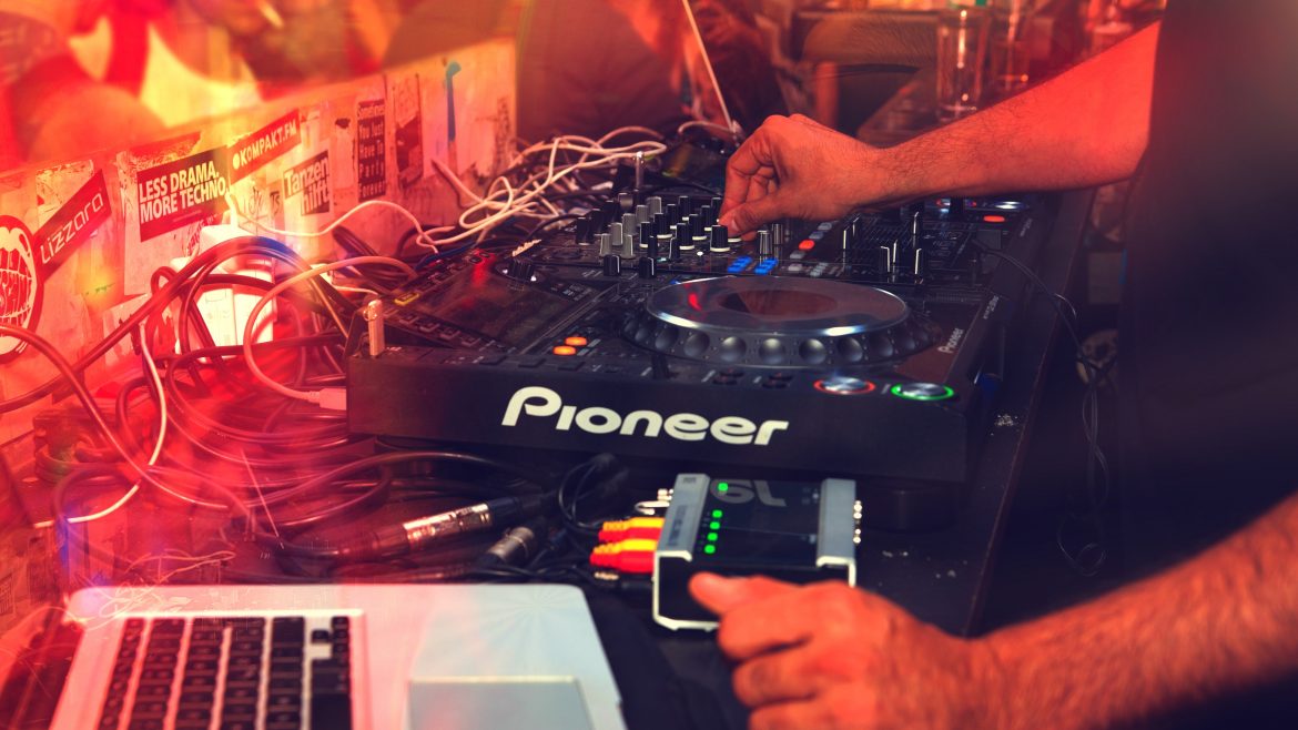 A DJs playing using on a Pioneer soundboard and a laptop