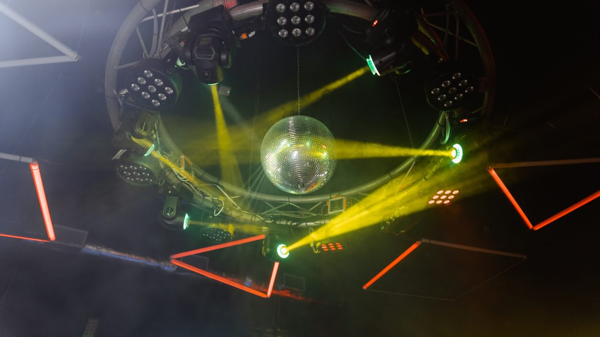A disco ball hanging from the ceiling of a club, surrounded by lights