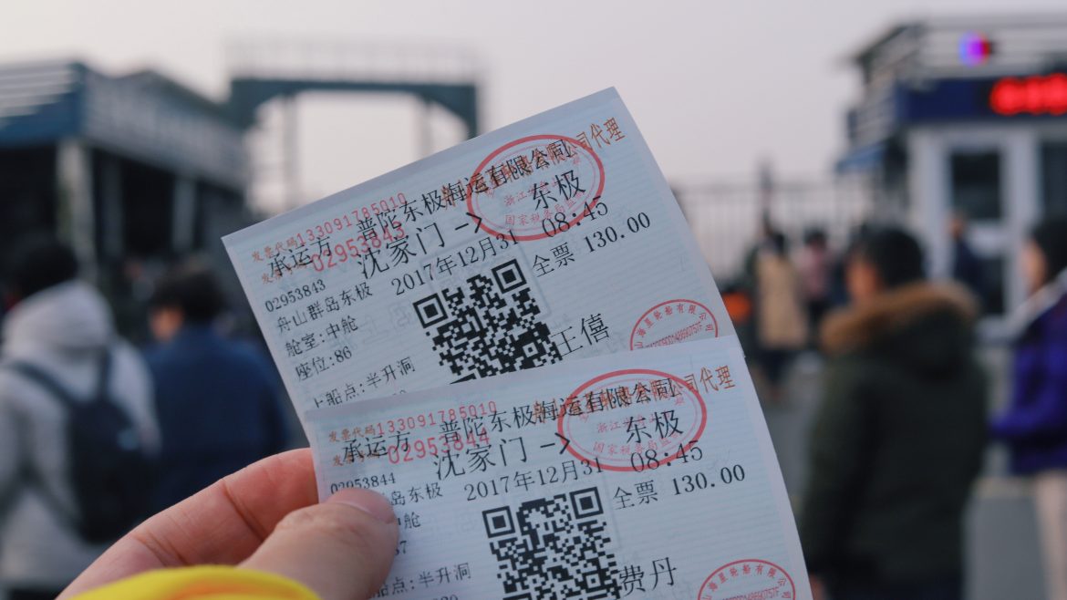 A hand holding two tickets in front of the camera