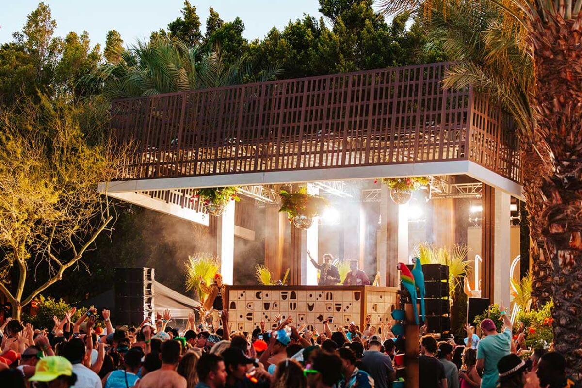 dj performing on stafe with crowd in an open area venue